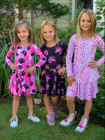 Three young girls wearing various pink outfits.