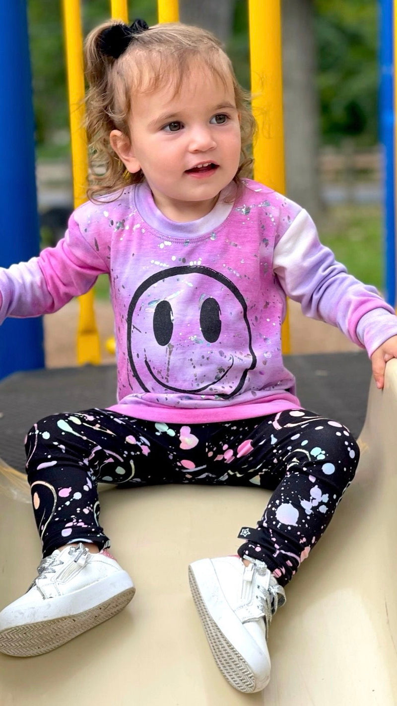 12 month old girl going down a slide on a playground.