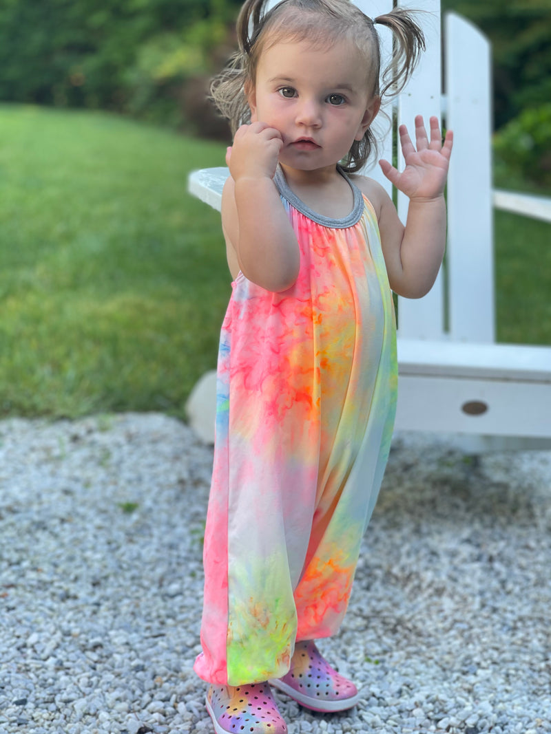 Toddler wearing a jumpsuit and standing in a driveway.
